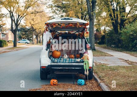 Trick o tronco. Bagagliaio bianco per auto decorato per Halloween. Decorazioni autunnali con zucche rosse e foglie gialle per la tradizionale vacanza all'aperto di ottobre. Foto Stock