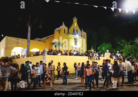 Merida, Messico - 31 ottobre 2018: Visitatori al festival per giorno dei morti seduti e camminando alla chiesa coloniale 'Santa Isabel' di notte Foto Stock