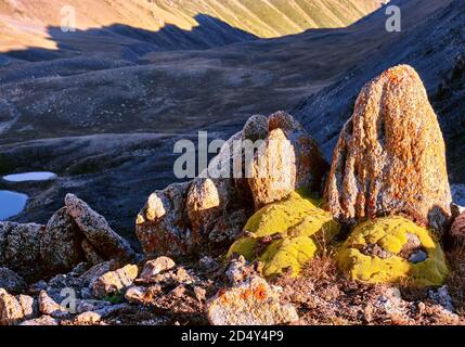 Spettacolari rocce di granito con licheni sullo sfondo del paesaggio alpino nelle alture; montagne del mattino all'alba Foto Stock