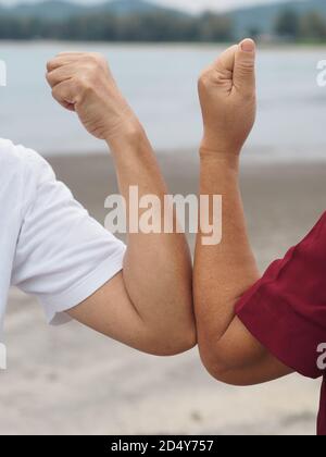 Due donne alternative handshakes Elbow Bump saluto nella situazione di un'epidemia covid 19, coronavirus nuovo normale di distanza sociale, verticale figu Foto Stock