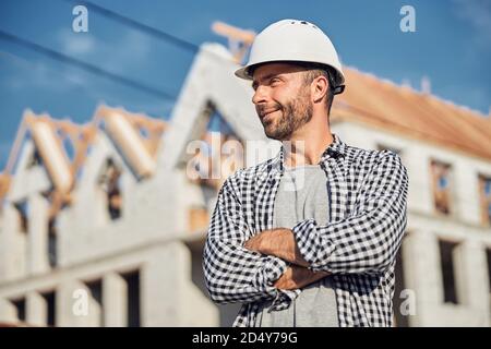 Allegro architetto in posa orgogliosamente di fronte al suo progetto di costruzione Foto Stock