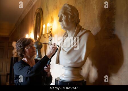 Un membro del personale del National Trust's Mottisfont in Hampshire, pulisce un busto di marmo nella Long Gallery, mentre preparano l'ex convento medievale prima di riaprire la casa ai membri del pubblico il lunedì, dopo il blocco del coronavirus. Foto Stock