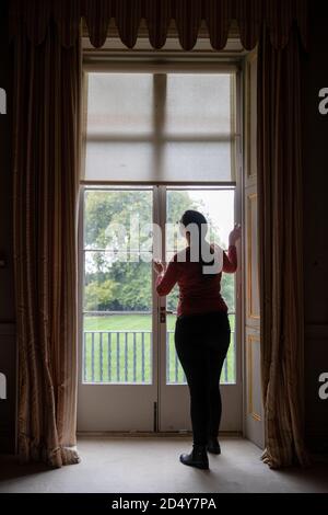 Un membro del personale del National Trust's Mottisfont in Hampshire, apre persiane e persiane mentre preparano l'ex convento medievale prima di riaprire la casa ai membri del pubblico il lunedì, dopo il blocco del coronavirus. Foto Stock