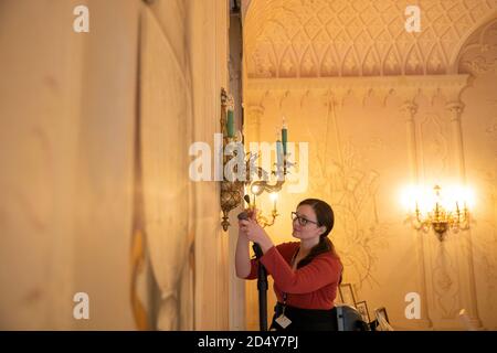 Un membro del personale del National Trust's Mottisfont in Hampshire, pulisce gli impianti di illuminazione nella Whistler Room, mentre preparano l'ex convento medievale prima di riaprire la casa ai membri del pubblico il lunedì, dopo il blocco del coronavirus. Foto Stock