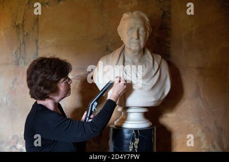 Un membro del personale del National Trust's Mottisfont in Hampshire, pulisce un busto di marmo nella Long Gallery, mentre preparano l'ex convento medievale prima di riaprire la casa ai membri del pubblico il lunedì, dopo il blocco del coronavirus. Foto Stock