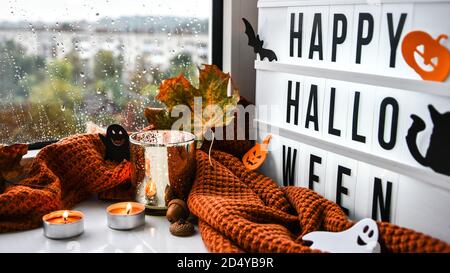 FELICE HALLOWEEN. Testo in scatola di luce bianca, con uno sfondo di maglione, foglie secche Halloween decorazione autunno sul davanzale. Finestra piovosa Foto Stock