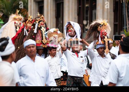 Galungan Vacanze. Uomini in abiti bianchi su una processione festosa con statue di divinità sulla testa. Isola di Bali, Indonesia. 26.12.2018. Foto Stock