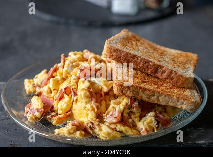 uova strapazzate con prosciutto e pane tostato su un piatto Foto Stock