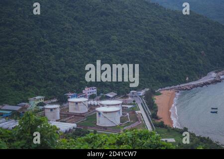 Terminale di carico dell'olio con grandi serbatoi di stoccaggio vicino al porto marittimo. Natura sera crepuscolo, boschi di fondo montagna, barche. Combustibile commerciale di affari Foto Stock
