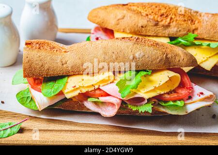 Sandwich di Baguette con carne, formaggio e verdure su tavola di legno. Foto Stock