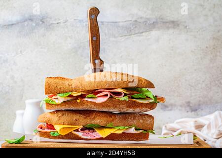 Sandwich di Baguette con carne, formaggio e verdure su tavola di legno. Foto Stock