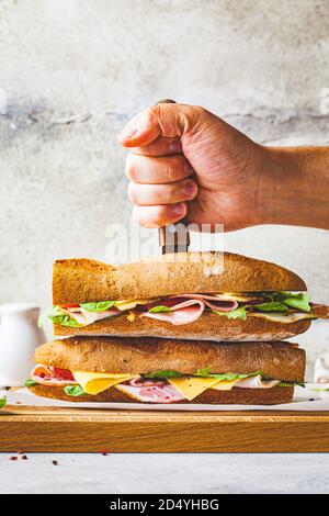 Sandwich di Baguette con carne, formaggio e verdure su tavola di legno. Foto Stock