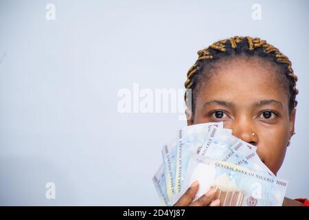 primo piano di donna africana che tiene un po 'di denaro su di lei faccia Foto Stock