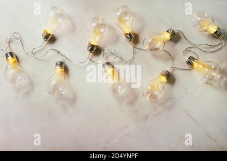 Retrò ghirlanda di Natale con le lampade accese su marmo bianco dello sfondo. Laici piana, spazio Foto Stock