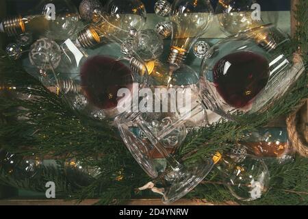 Due bicchieri di vino rosso e retrò ghirlanda di Natale con le lampade accese su marmo bianco dello sfondo. Laici piana, spazio Foto Stock