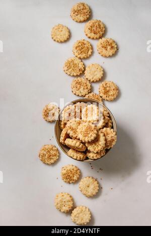 Snack caserecci frollini formaggio biscotti di sesamo nella ciotola su marmo bianco dello sfondo. Laici piana, spazio Foto Stock
