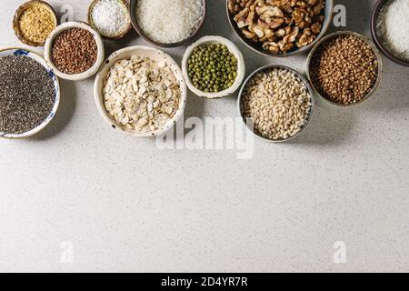 Varietà di materie non cotti i grani di cereale super chia, biancheria, sesamo, Mung bean, noci, tapioca, frumento, grano saraceno, fiocchi d'avena, noce di cocco, riso in ceramica Foto Stock