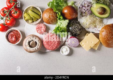 Ingredienti per la cottura tradizionale fatta in casa e piatti vegan hamburger. Carne hamburger di manzo, formaggio, avocado, Portobello, pomodoro, in bianco e nero panini, insalate, Foto Stock