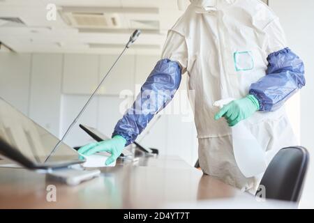 Ritratto troncato di operatore sanitario che indossa una muta per la pulizia e la disinfezione della sala conferenze in ufficio, copia spazio Foto Stock