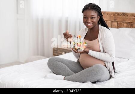 Nutrizione sana di gravidanza. Felice incinta Africana americana Donna mangiare fresco insalata di verdure Foto Stock