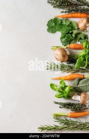 Varietà di cucina fresca erbe con mini carote e funghi champignon in fila su marmo bianco dello sfondo. Appartamento laico, spazio. Concetto di cucina a vista, cibo Foto Stock