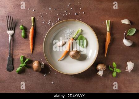 Varietà di cucina fresca erbe con mini carote e funghi champignon in fila su marmo bianco dello sfondo. Appartamento laico, spazio. Concetto di cucina a vista, cibo Foto Stock