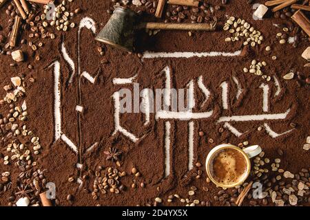 Iscrizione calligrafico lettere gotiche caffè sulla massa di caffè nero sparsi su marmo bianco con arrosti e i fagioli non torrefatto, pot, tazza di espres Foto Stock