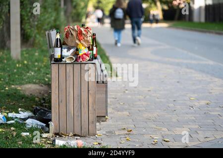 Cestino di spazzatura sovraffollato in strada. Cestino. Un mucchio di rifiuti di plastica sul pavimento e l'erba. Foto Stock