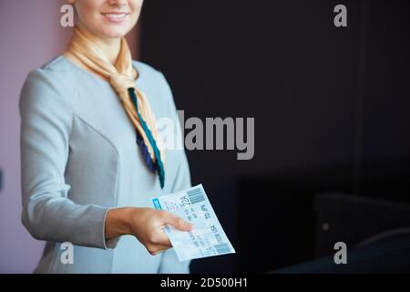 Ritratto troncato di sorridente assistente di volo che consegna i biglietti al passeggero mentre si trova al banco del check-in in aeroporto, spazio fotocopie Foto Stock