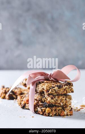 Energia in casa di avena granola bar con frutta secca e noci intere e rotto con nastro rosa sulla tabella grigia. Snack sani. Foto Stock