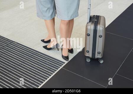 Bassa sezione di sfondo di due eleganti giovani donne che indossano tacchi in piedi da valigia in aeroporto, spazio copia Foto Stock