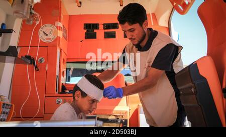 l'infermiera abbraccia un bambino e lo cura all'interno dell'ambulanza. Foto Stock