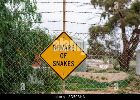 Attenzione ai serpenti segno giallo sulla recinzione del filo nel NSW Australia Foto Stock