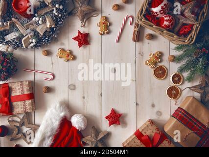 Buon Natale e buone feste! Baubles, regali, caramelle con ornamenti su scrivania in legno. Vista dall'alto. Tradizioni natalizie. Foto Stock