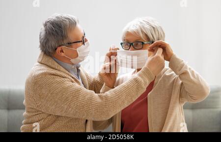 Coppia senior che indossa maschere durante il coronavirus e l'epidemia di influenza. Protezione contro virus e malattie, quarantena domestica. COVID-2019. Assunzione o presa di Foto Stock