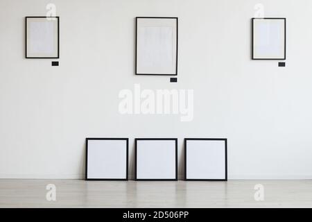 Immagine di sfondo di cornici nere vuote appese sulla parete bianca della galleria d'arte, spazio di copia Foto Stock