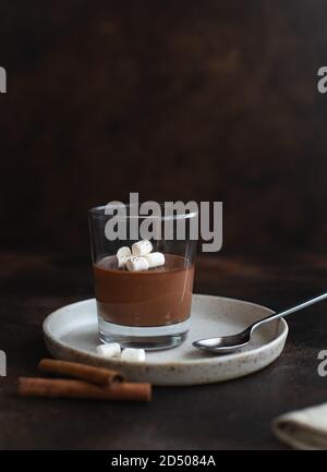 Deliziosa panna cotta di dessert italiano con cioccolato fondente, decorata con marshmallows. Sfondo scuro Foto Stock