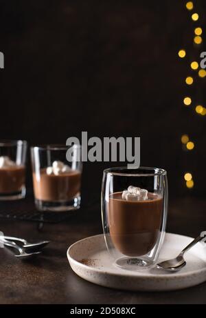 panna cotta da dessert in vetro a doppia parete, decorata con marshmallows. sfondo di natale sfocato Foto Stock