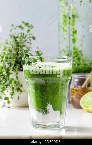 Gli spinaci verde kale apple frullato di miele con yogurt e timo in vetro bianco sulla tavola di marmo con Blender e gli ingredienti di cui sopra. Sana eatin organico Foto Stock