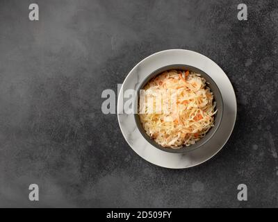 cavolo fermentato fatto in casa in una ciotola. insalata vegana sana. fondo in cemento scuro, vista dall'alto Foto Stock