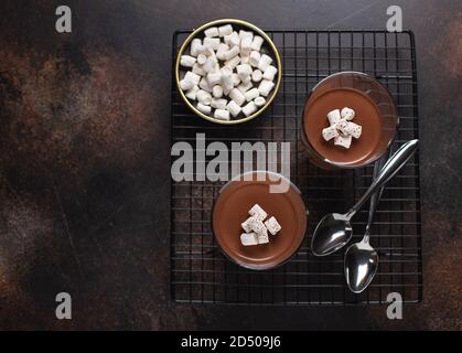 panna cotta al cioccolato con marshmallows. marrone monocromatico. sfondo a trama scura, spazio copia, vista dall'alto Foto Stock