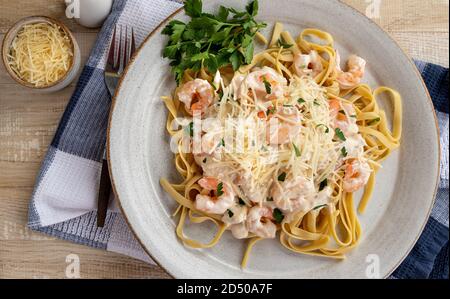 Fettuccine cremose alfredo con gamberi e parmigiano grattugiato su un piatto. Vista dall'alto Foto Stock