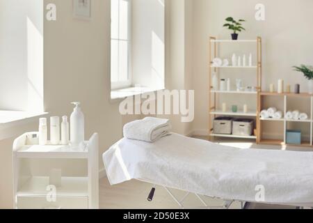 Sala massaggi o salone di bellezza con letto vuoto e pronto set di prodotti biologici per la cura della pelle Foto Stock