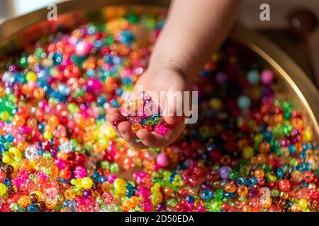 Perle colorate nei palmi del bambino. Uno sfondo molto colorato di perle scintillanti Foto Stock