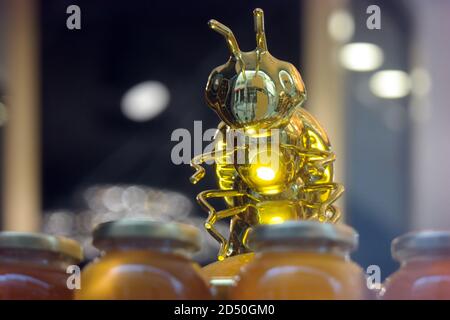 Figurine dell'ape da vetro e miele di fiore. Il miele fresco è con le erbe. Dolce. Foto Stock