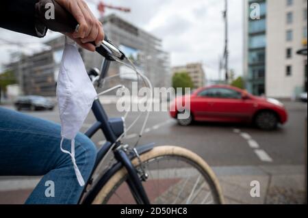 12 ottobre 2020, Baden-Wuerttemberg, Stoccarda: Una donna sta in piedi sul City Ring con la sua bicicletta, sulla quale è fissata una guardia per bocca e naso. Sabato 10 ottobre 2020 a Stoccarda è stato superato il valore di allarme di 50 nuove infezioni ogni 100,000 abitanti in sette giorni. A partire da mercoledì 14 ottobre, le maschere saranno obbligatorie nel centro della città all'interno del City Ring. Foto: Sebastian Gollnow/dpa Foto Stock