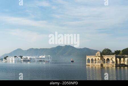 Vista del lago Pichola e Lake Palace hotel con le colline di Aravalli in background su una mattina luminosa a Udaipur, Rajasthan, India. Foto Stock