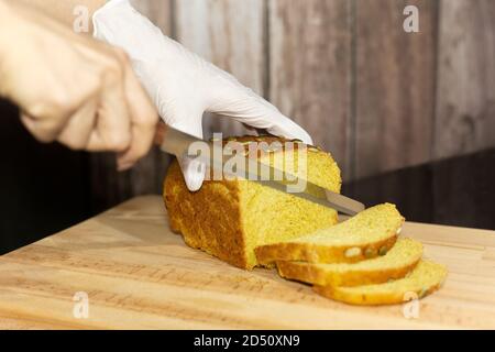 Lo chef taglia il pane di zucca sulla tavola di legno, fuoco selettivo. Foto Stock