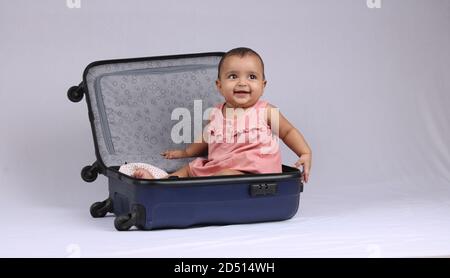 Viaggi, bambini, vacanze - Funny baby girl seduta e sorridente in valigia blu. Foto Stock