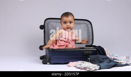 Viaggi, bambini, vacanze - Funny baby girl seduta e sorridente in valigia blu. Foto Stock